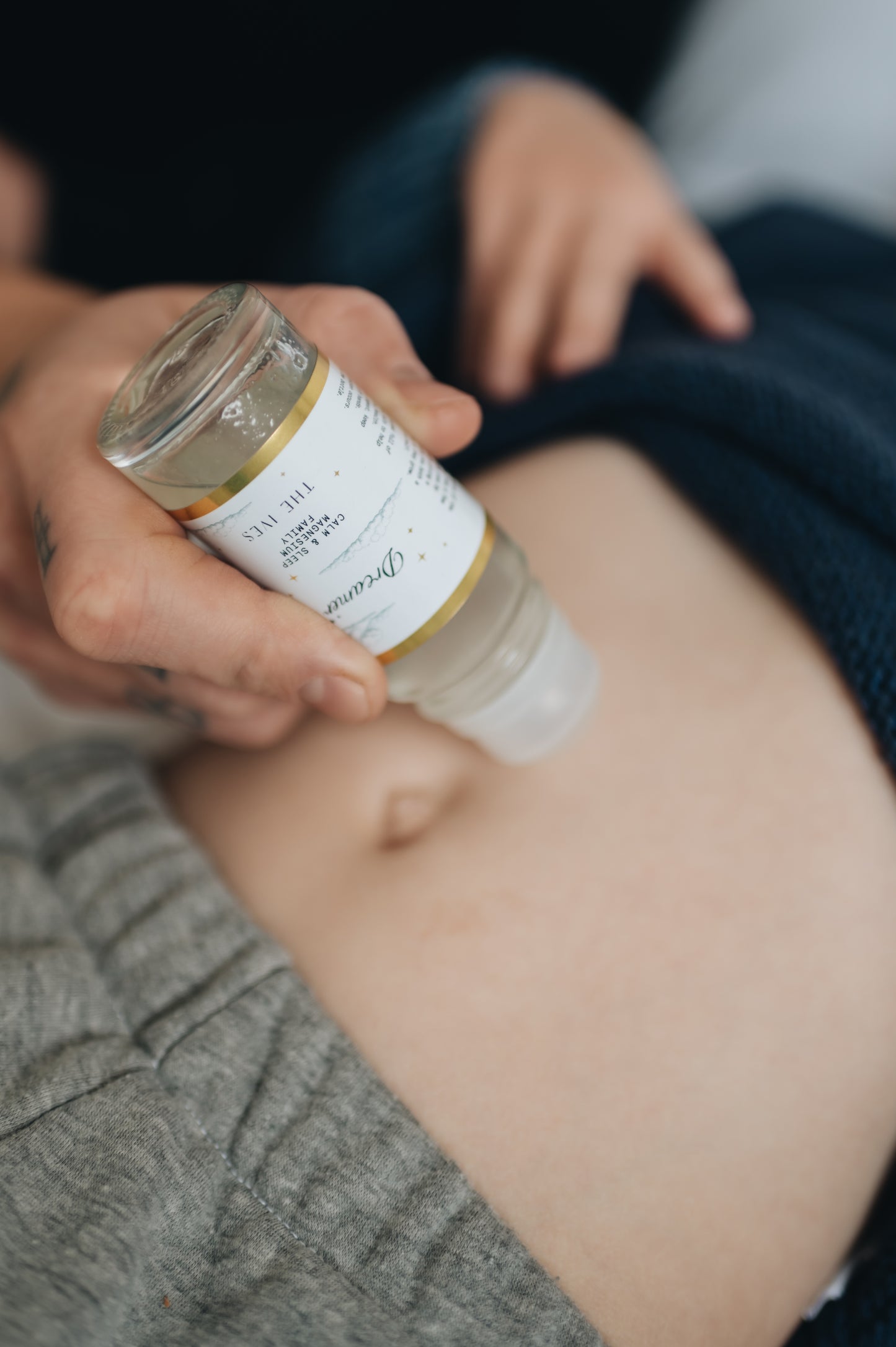sleep roller massaged onto the skin of a child to help with sleep, natural sleep aid with magnesium oil and essential oils for sleep. Man holding glass roller and rolll-on the childs skin for sleep