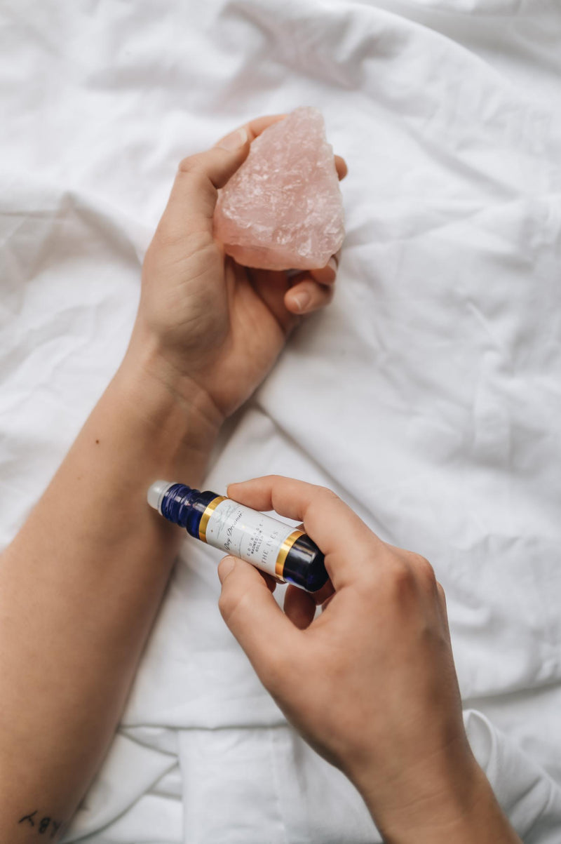 magnesium oil anxiety roller used on pulse points of the writs, holding pink rose quartz crystal in hand, use when anxiety strikes and smell the essential oils blend.